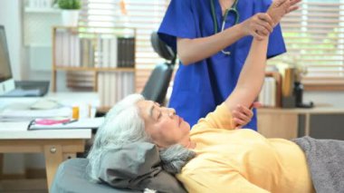 Rehabilitasyon kliniğinde yaşlı, donmuş omuz semptomlarını inceleyen kadın doktor..