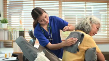 Fizyoterapist, ciğerlerindeki salgıları gevşetmek ve boşaltmak için kıdemli bir hastaya perküsyon uyguluyor..