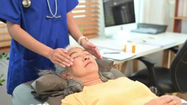 Reiki tedavisini uygulayan fizyoterapist olgun kadın kafasının üstündeki iyileşme enerjisini kanalize ediyor..