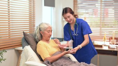 Fizyoterapist olgun bir kadına akciğerlerin işleyişini geliştirmek için spirometre kullanmasında yardım ediyor..