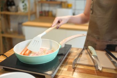 Genç bir kadının mutfağında kahvaltı hazırlarken çekilmiş bir fotoğrafı..