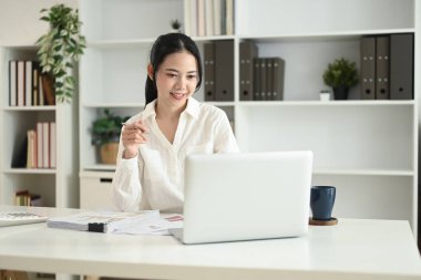 Laptopla çalışan ve masa başında belgeleri inceleyen çekici genç girişimci..