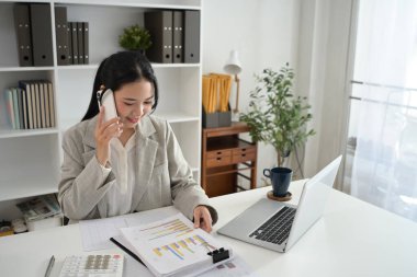 Başarılı bir iş kadını telefon görüşmesi yapıyor ve mali belgeleri kontrol ediyor..
