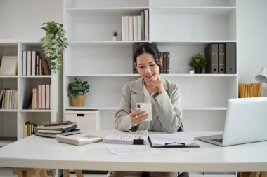 Başarılı genç girişimci masasında akıllı telefon kullanıyor..