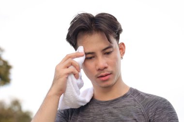 Yorgun genç sporcu beyaz bir havluyla yüzünden ter silmeye ara veriyor..