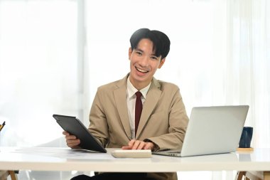 Modern çalışma alanında çalışan resmi takım elbiseli neşeli genç girişimci..