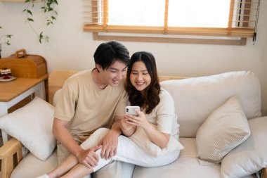 Evde akıllı telefondan eğlenceli anlar paylaşan sevimli genç bir çift..