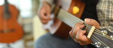 Genç adamın akustik gitar çalışına yakın çekim. Boş zaman aktivitesi ve hobi konsepti.