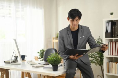 Genç profesyonel işadamı iş yerindeki belgeleri kontrol ediyor.