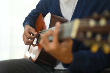 Genç adamın akustik gitar çalışına yakın çekim. Boş zaman aktivitesi ve hobi konsepti.