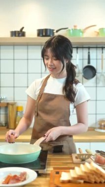 Sıcak bir mutfakta yumurta kıran genç bir kadın..