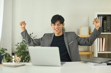 Heyecanlı genç girişimci iş yerinde olumlu iş sonuçlarını kutluyor.