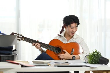 Tatilde iş yerinde gitar çalan neşeli bir çalışan..
