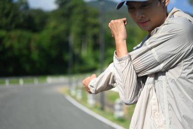 Genç adam spor yaparken yolda esneme hareketleri giyer..