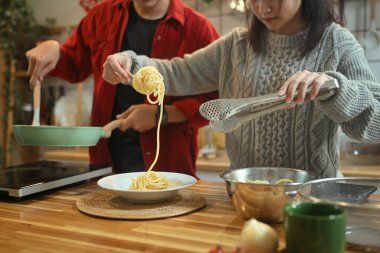 Genç evli, güzel bir çift, süveter giyip Noel günü mutfakta yemek hazırlıyorlar..
