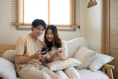 Rahat Asyalı çift oturma odasındaki akıllı telefondan online içeriği izliyor..