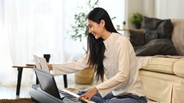Genç bir kadın evde piyano çalışıyor ve nota okuyor..