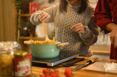 Genç evli, güzel bir çift, süveter giyip Noel günü mutfakta yemek hazırlıyorlar..