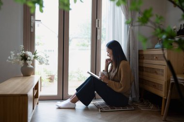 Huzurlu genç kadın günlüğünü yazıyor ve pencerenin kenarında sıcak bir içecekle rahatlıyor..