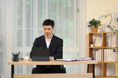 Modern ofiste dijital tablet üzerinde çalışan siyah takım elbiseli girişimci.