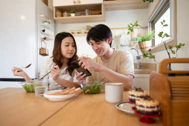 Mutfakta öğle yemeği sırasında akıllı telefon kullanan mutlu genç çift..