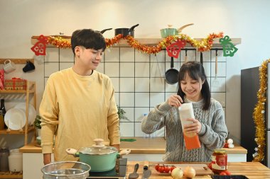 Gülümseyen genç çift sıcak bir tatil yemeği hazırlıyor..