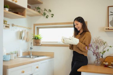 Sıcak, modern bir mutfakta fırın eldiveni olan mutlu bir milenyum kadını..