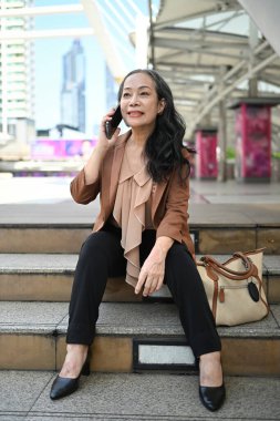 Kendine güveni tam bir girişimci. Telefonuyla konuşuyor. Şehrin dışında oturuyor..