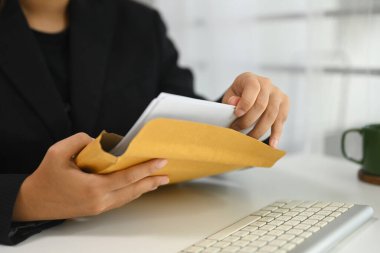 Ofis çalışanı iş işlemleri için belgeleri zarfın içinde hazırlıyor..