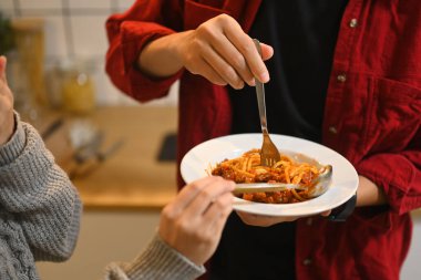Tatil sezonunda sıcak ışıklandırmayla bir tabak spagetti paylaşan çift..
