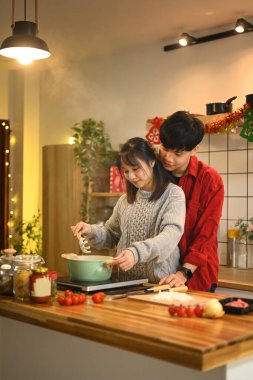 Gülümseyen genç çift sıcak mutfaktaki Noel yemeğine hazırlanıyor..