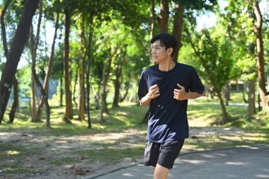 Genç Asyalı bir adam doğada sabah koşusundan zevk alıyor. Sağlık ve Sağlıklı Yaşam Konsepti.