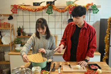 Çekici genç çift Noel arifesinde mutfakta akşam yemeği hazırlıyor..