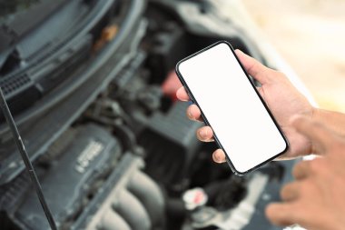 Otomotiv tanılama ya da acil durum hizmetleri için mobil uygulama ya da çevrimiçi yardım kullanan bir adam.