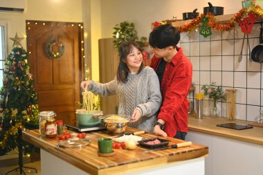 Çekici genç çift Noel arifesinde mutfakta akşam yemeği hazırlıyor..