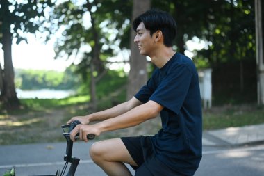 Güzel bir günde parkta bisiklet süren genç bir adamın fotoğrafı..