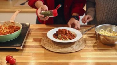 İnsan bolonez servis etmeden önce spagetti sosuna otlar serpiyor..