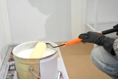 Bir ev geliştirme projesi sırasında işçilerin beyaz boya kutusuna fırça batırırken yakın plan çekimleri..