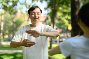 Sabahları gülümseyen orta yaşlı adam Tai Chi çalışıyor. Akıl sağlığı ve refah. Konsept..