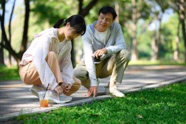Baba ve kızı güzel bir parkta koşmadan önce ayakkabı bağcıklarını bağlıyorlar. Sağlık ve refah kavramı.