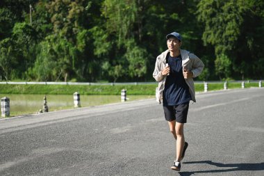 Genç atletik bir adam barışçıl doğal ortamda koşmaktan zevk alıyor. Sağlıklı yaşam tarzı kavramı.