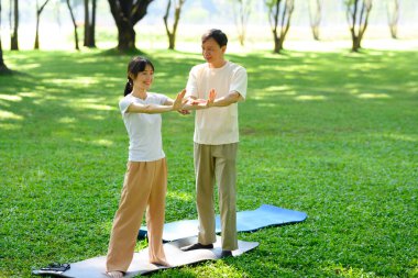 Baba ve kızı huzur parkında Tai Chi çalışıyor. Farkındalık ve sağlık kavramı.