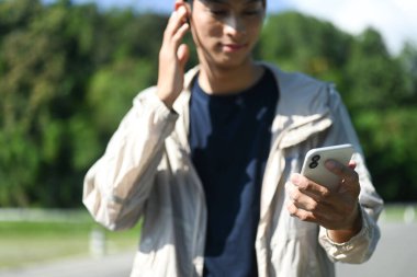 Gülümseyen adam antreman arasında müzik dinliyor ve telefona bakıyor..
