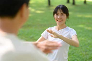Neşeli Asyalı kadın ve baba parkta Tai Chi çalışıyor. Sağlıklı ve açık hava aktivitesi kavramı.