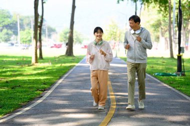 Mutlu orta yaşlı baba ve kızı güzel bir parkta koşuyor. Sağlık ve aile faaliyeti kavramı.