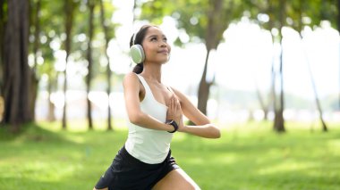 Elleri dua ederken poz veren genç Afrikalı kadın huzur parkında yoga yapıyor..