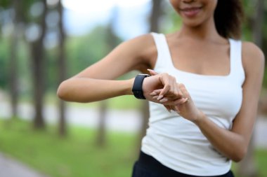 Gülümseyen sporcu kadın, dışarıda egzersiz yaparken izlediği ukala hareketlerini izliyor..