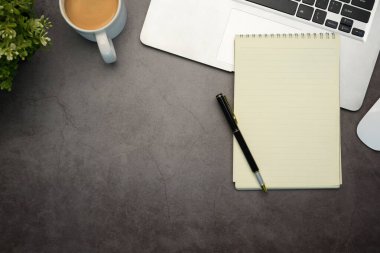 Düz dizüstü bilgisayar, dizüstü bilgisayar ve bir fincan kahveyi düz bir şekilde koyu renkli bir taşın üzerine serpiştirirdi..