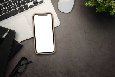 Akıllı telefon, dizüstü bilgisayar ve parlak, koyu renkli bir taş üzerine dizüstü bilgisayarı olan yaratıcı çalışma alanı.