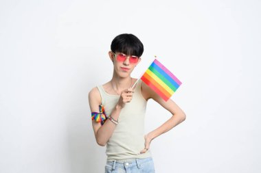 Pembe güneş gözlüklü genç adamın portresi gökkuşağı gurur bayrağı taşıyor. İnsan hakları ve LGBTQ toplum kavramı.